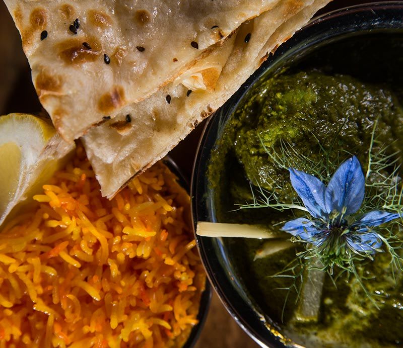 Tradycyjne danie z aromatycznym żółtym ryżem, zielonym curry i świeżym chlebkiem naan.